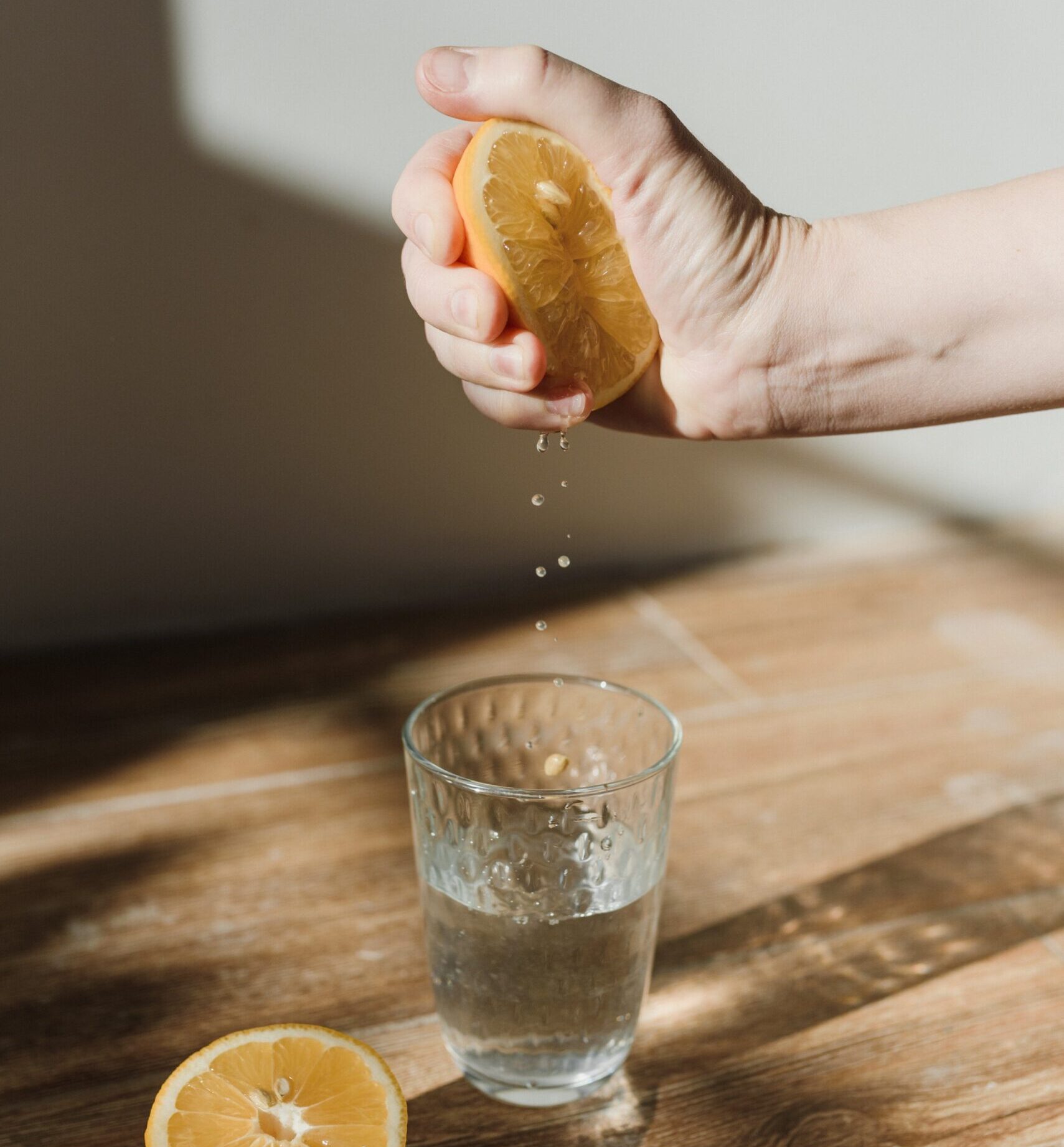 hand squeezing a lemon into a glass of water