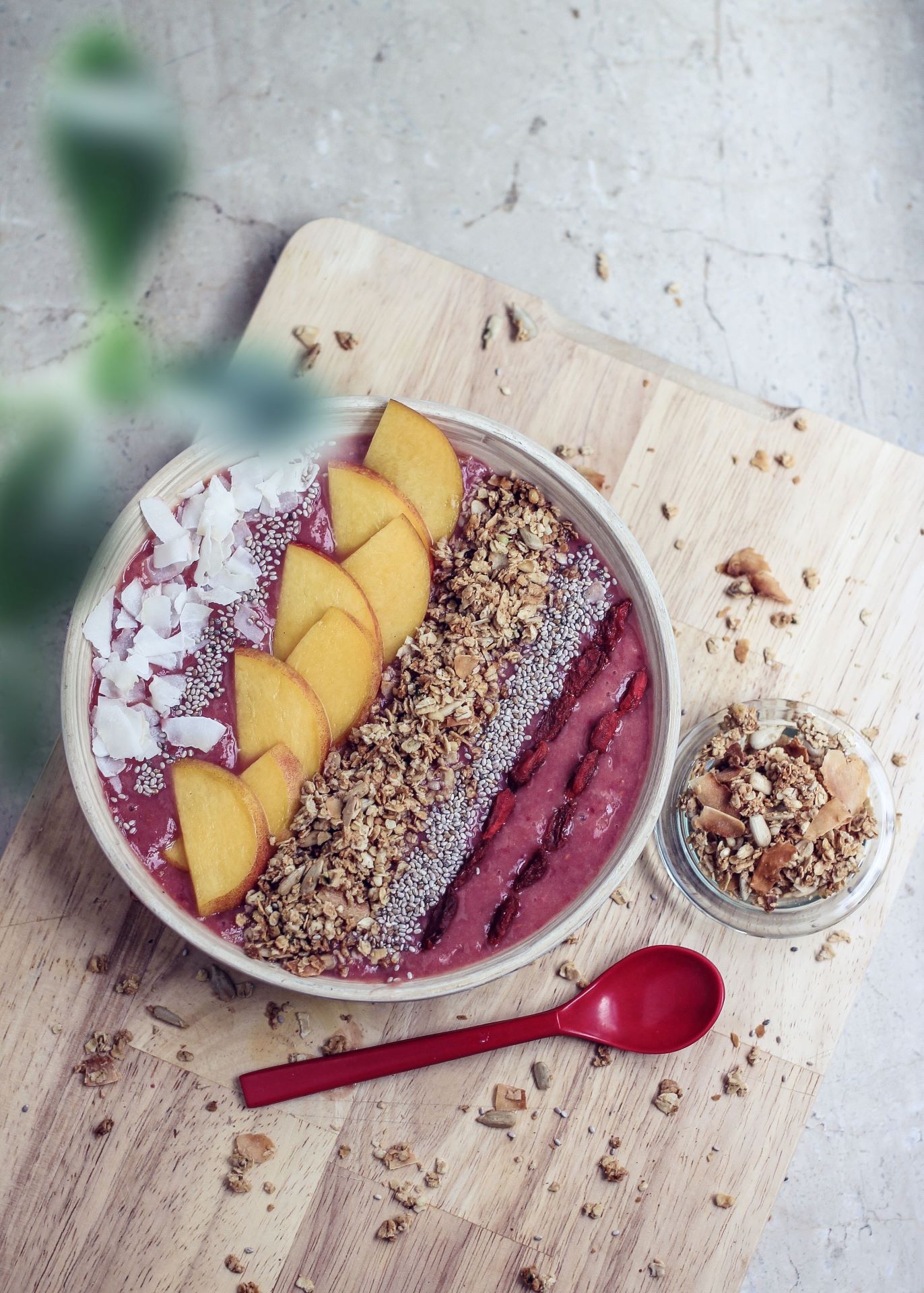 Smoothie bowl topped with coconut flakes, fruit, muesli and chia seeds on a wooden board 