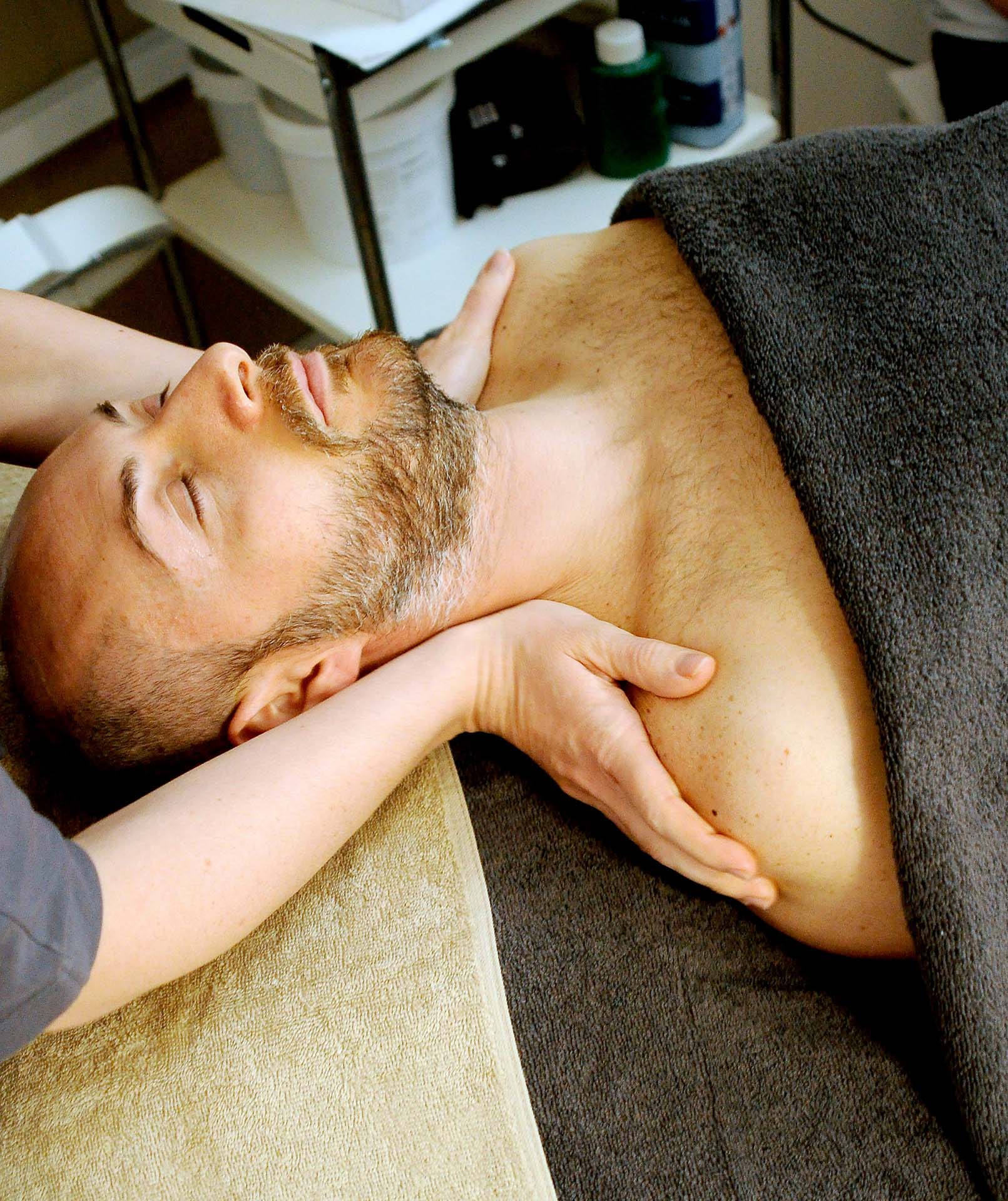 man laying on a chiropractor table with a physio treating his shoulders