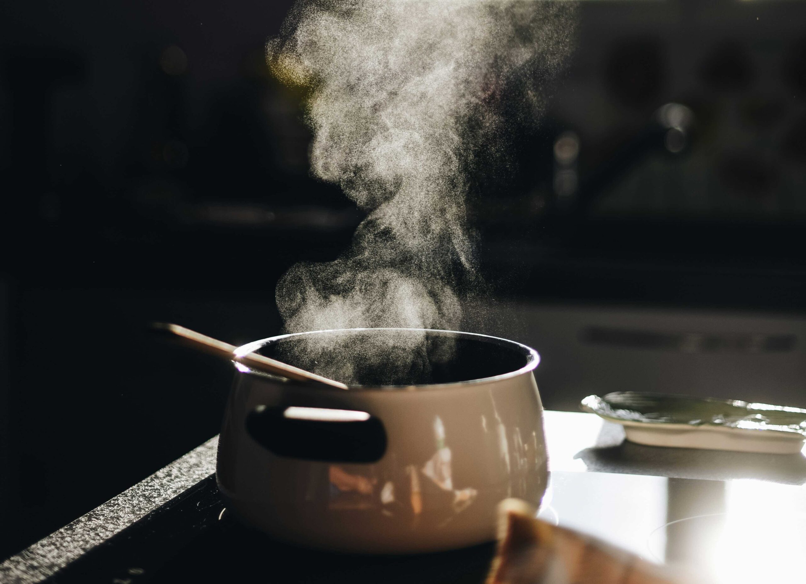 steam rising above a pot of hot soup on the stove