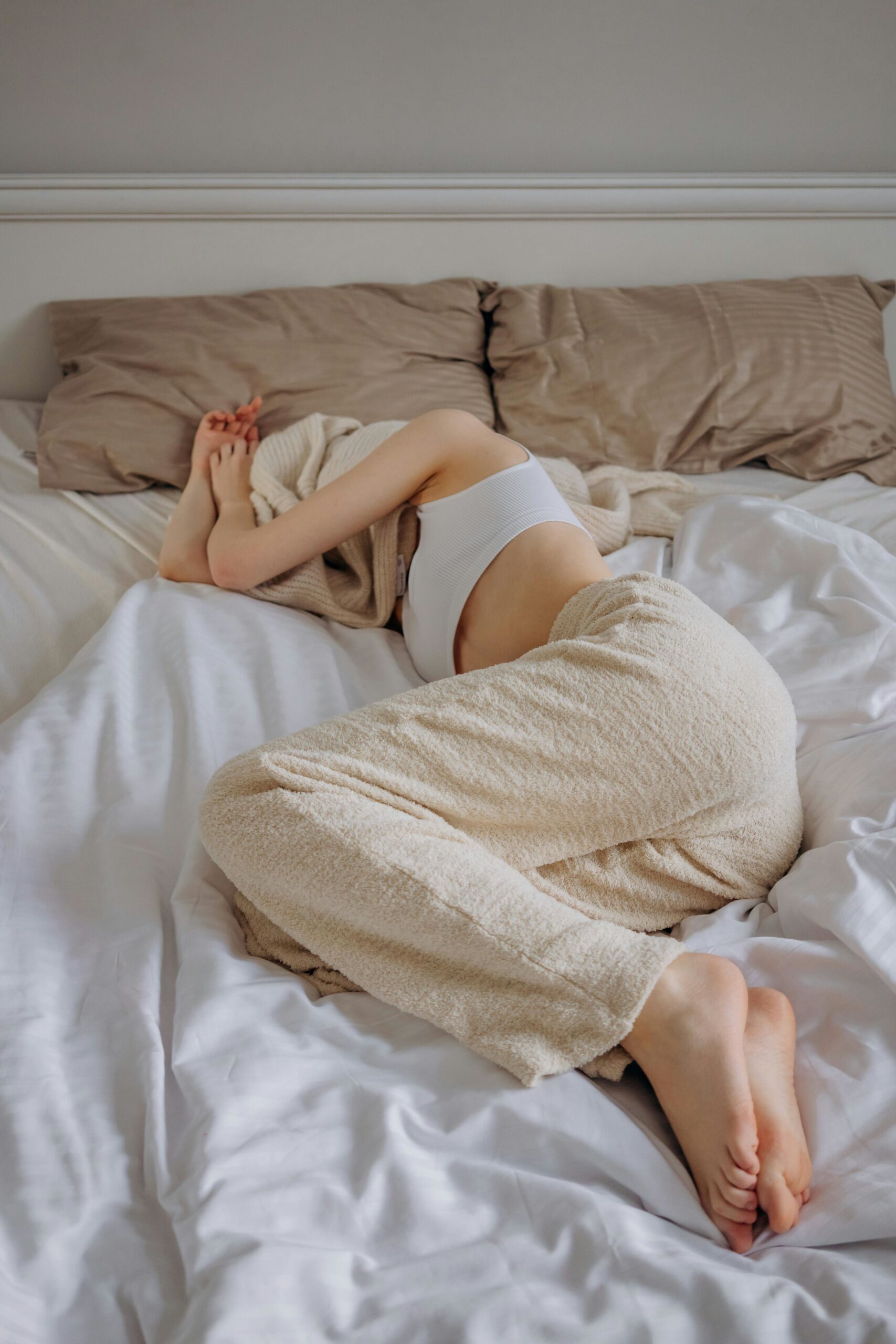 woman lying in bed with  blanket or towel over head